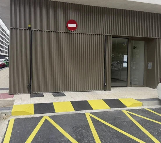 Vado de garaje recién pintado con señalización horizontal amarilla y negra, trabajo real